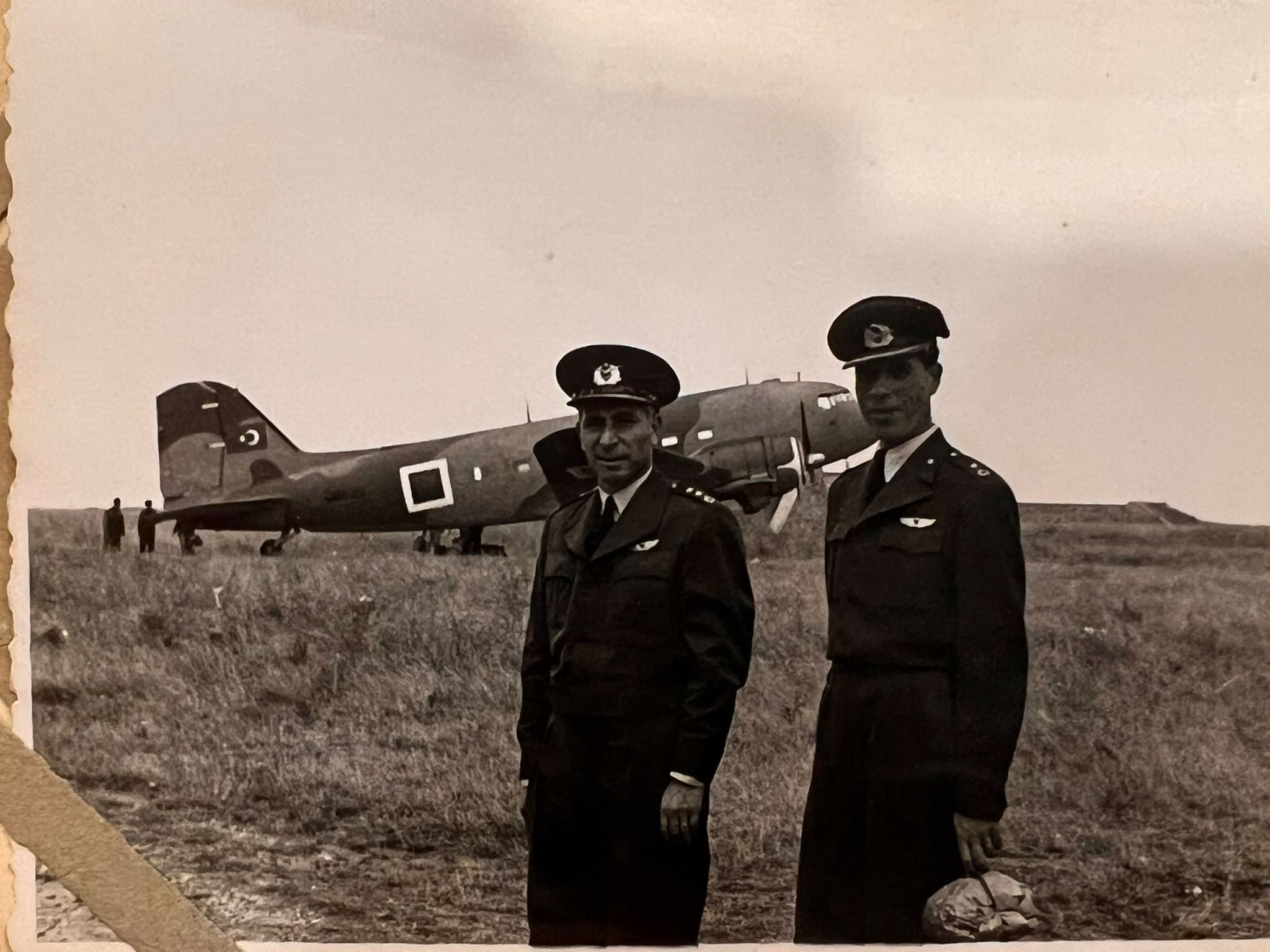 Bir uçuş sahasında, askerî uçağın yanında iki subay.